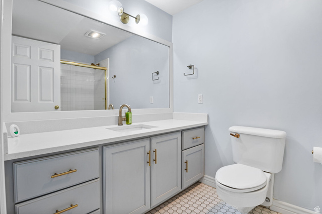 576 East 3950 North Provo, UT 84604 - Photo 30 of 47 White hexagonal floor tiling, a light gray vanity with gold-tone hardware, and a white countertop with an integrated sink