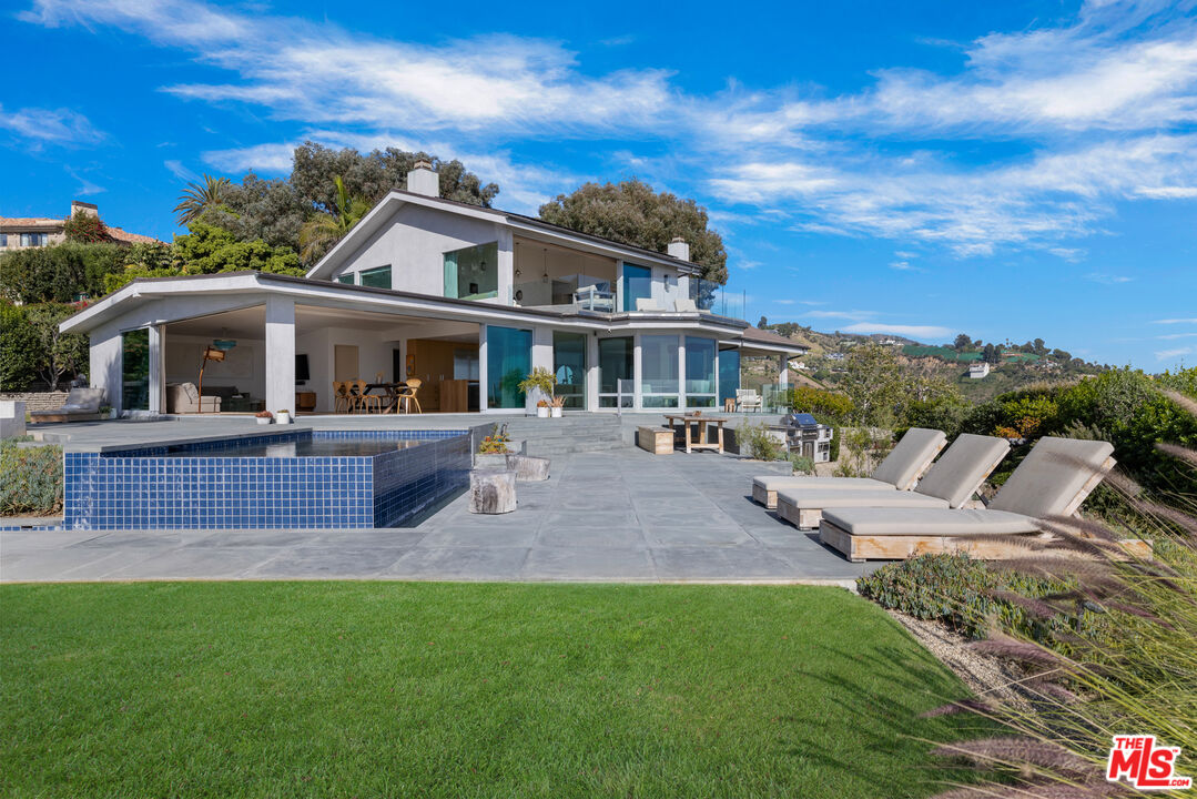 22407 Carbon Mesa Road Malibu, CA 90265 - Photo 24 of 33 a front view of a house with garden and trees
