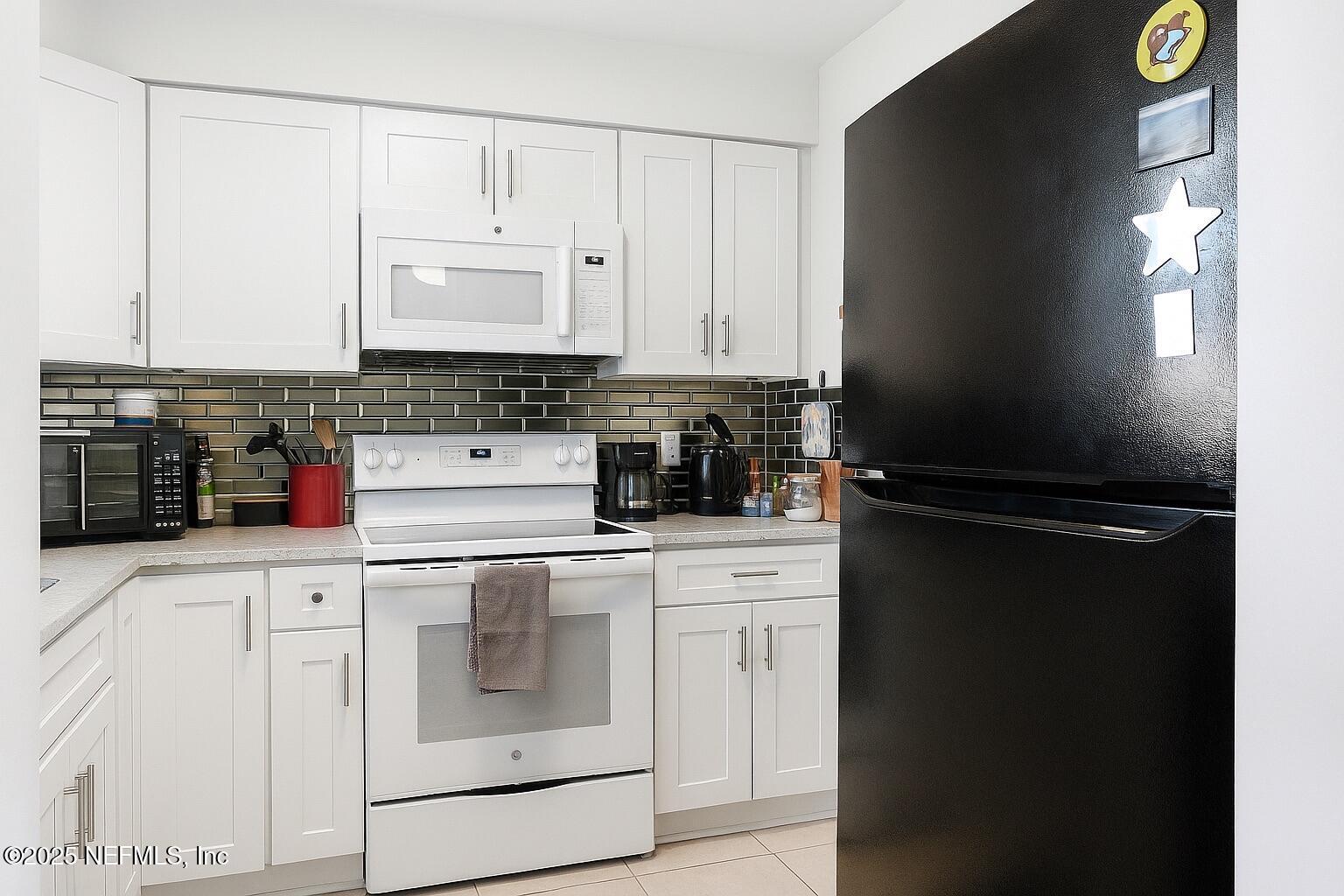 7341 El Ocho Road, Unit 5 Jacksonville, FL 32216 - Photo 8 of 9 a kitchen with a refrigerator and white cabinets