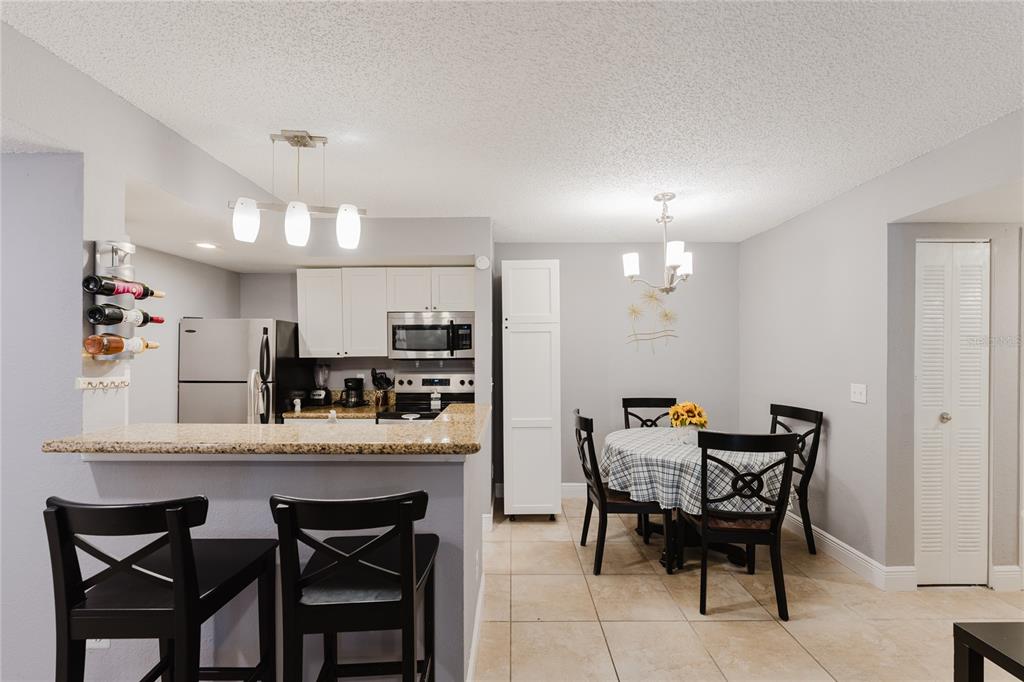 5120 Conroy Road, Unit 18 Orlando, FL 32811 - Photo 14 of 38 a dining room with kitchen island a dining table chairs with wooden floor and appliances