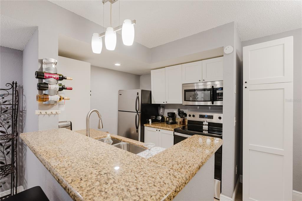 5120 Conroy Road, Unit 18 Orlando, FL 32811 - Photo 10 of 38 a kitchen with stainless steel appliances granite countertop a sink refrigerator and microwave