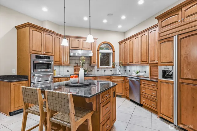 a kitchen with stainless steel appliances granite countertop a stove top oven a sink refrigerator and cabinets