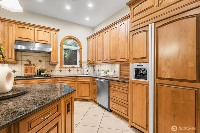 a kitchen with stainless steel appliances granite countertop a stove a sink and a refrigerator