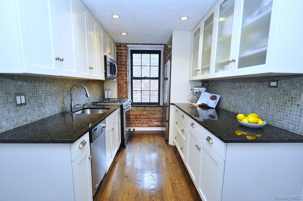 105 Garth Road, Unit 1L Scarsdale, NY 10583 - Photo 1 of 1 new 17' eat-in-kitchen with an exposed brick wall, granite counters, high end stainless steel appliances including a five (5) burner slide in range and sleek French door refrigerator, custom white 48" cabinets and recessed lighting. There is even a widow for natural light and ventilation.