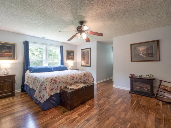 a spacious bedroom with a bed and dresser with wooden floor