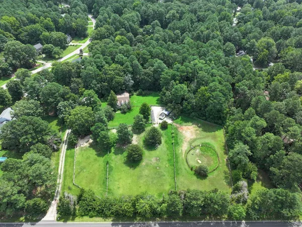 an aerial view of residential house with outdoor space and trees all around