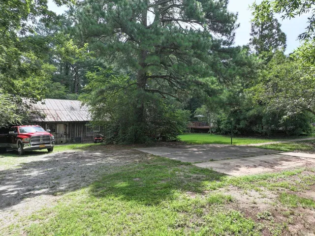 a view of a house with a big yard plants and large trees