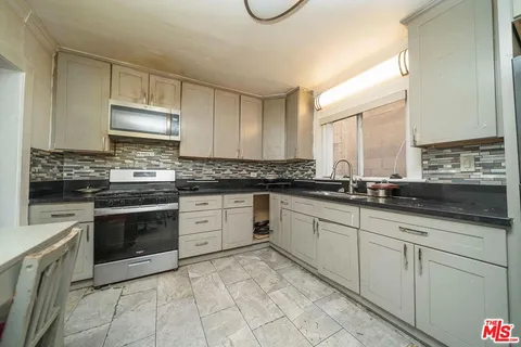 a kitchen with granite countertop white cabinets sink and stainless steel appliances