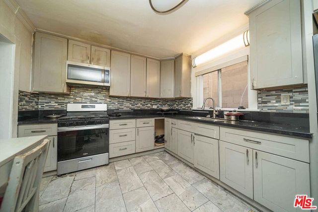 a kitchen with granite countertop white cabinets sink and stainless steel appliances