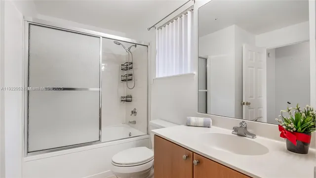 a bathroom with a shower sink vanity mirror and toilet