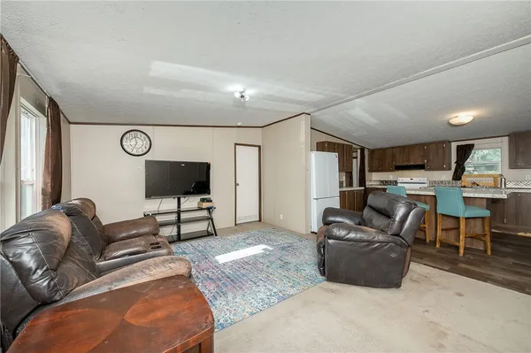 a living room with furniture kitchen view and a flat screen tv