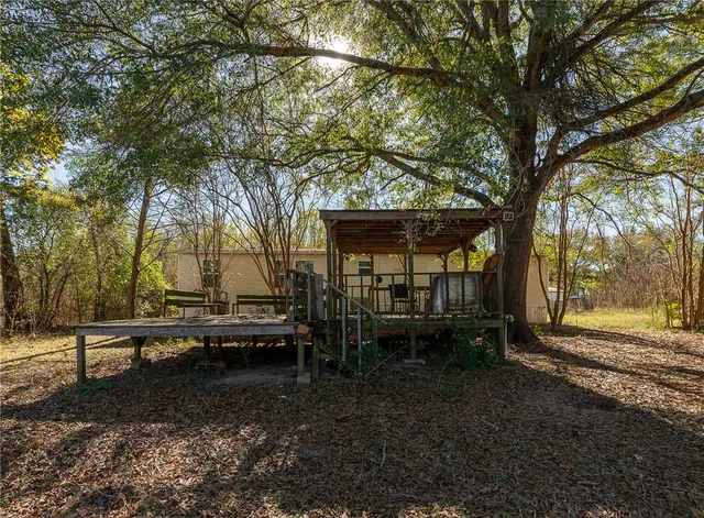 a backyard of a house with table and chairs under an umbrella