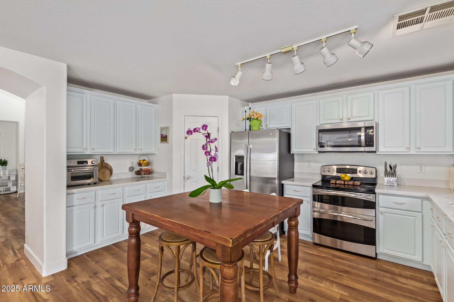 45360 West Desert Garden Road Maricopa, AZ 85139 - Photo 17 of 42 a kitchen with stainless steel appliances granite countertop a stove a refrigerator a sink a dining table and chairs with wooden floor