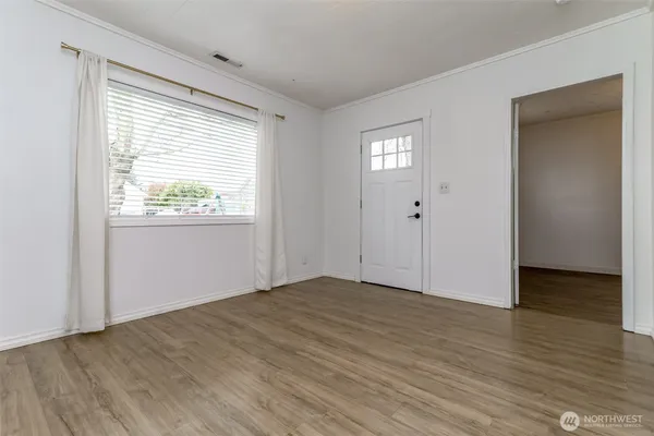 a view of an empty room with wooden floor and a window