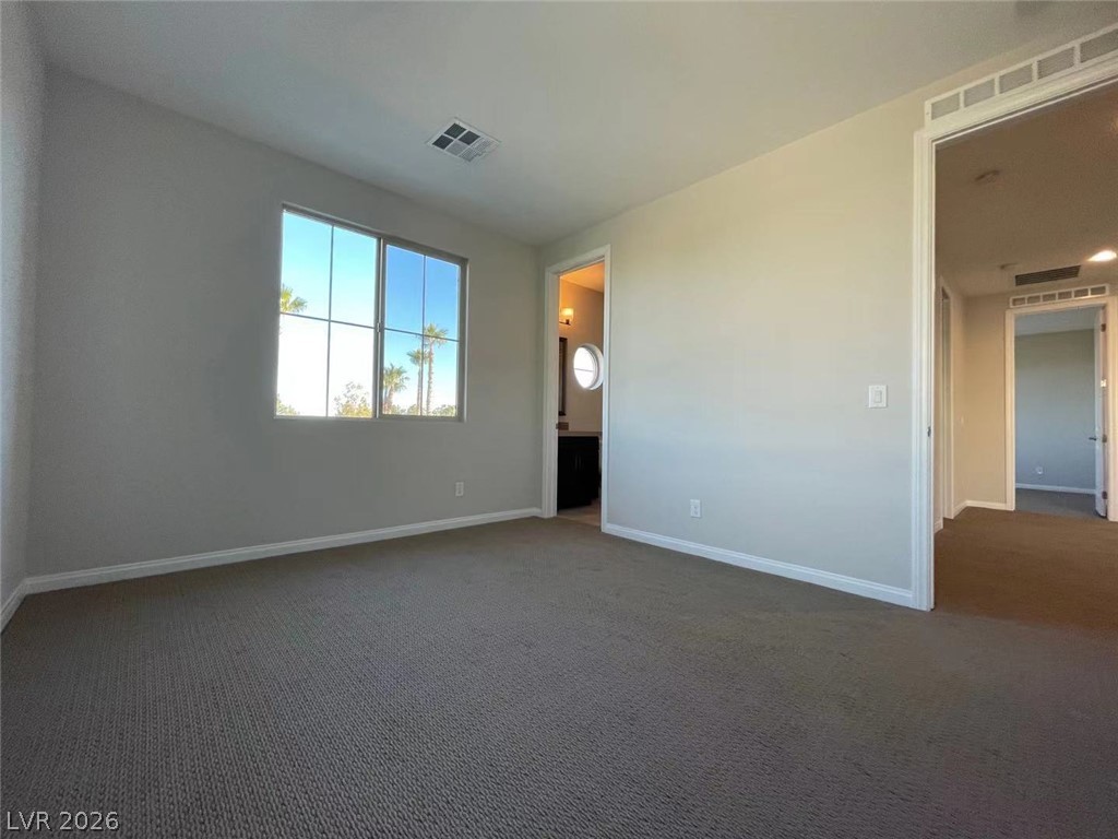 11 Rancho Maria Street Las Vegas, NV 89148 - Photo 23 of 27 A light-filled room showcases wall-to-wall carpeting and a wide window overlooking palm trees.