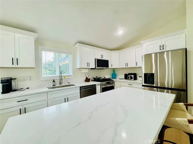 a kitchen with granite countertop a refrigerator stove microwave and sink