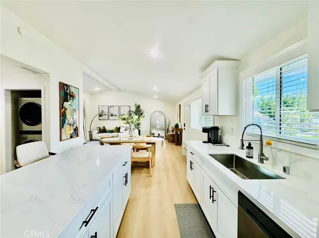 a large white kitchen with a window a sink a counter space and stainless steel appliances