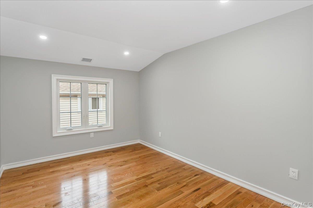 243-36 Caney Road Queens, NY 11422 - Photo 23 of 30 a view of empty room with wooden floor and fan