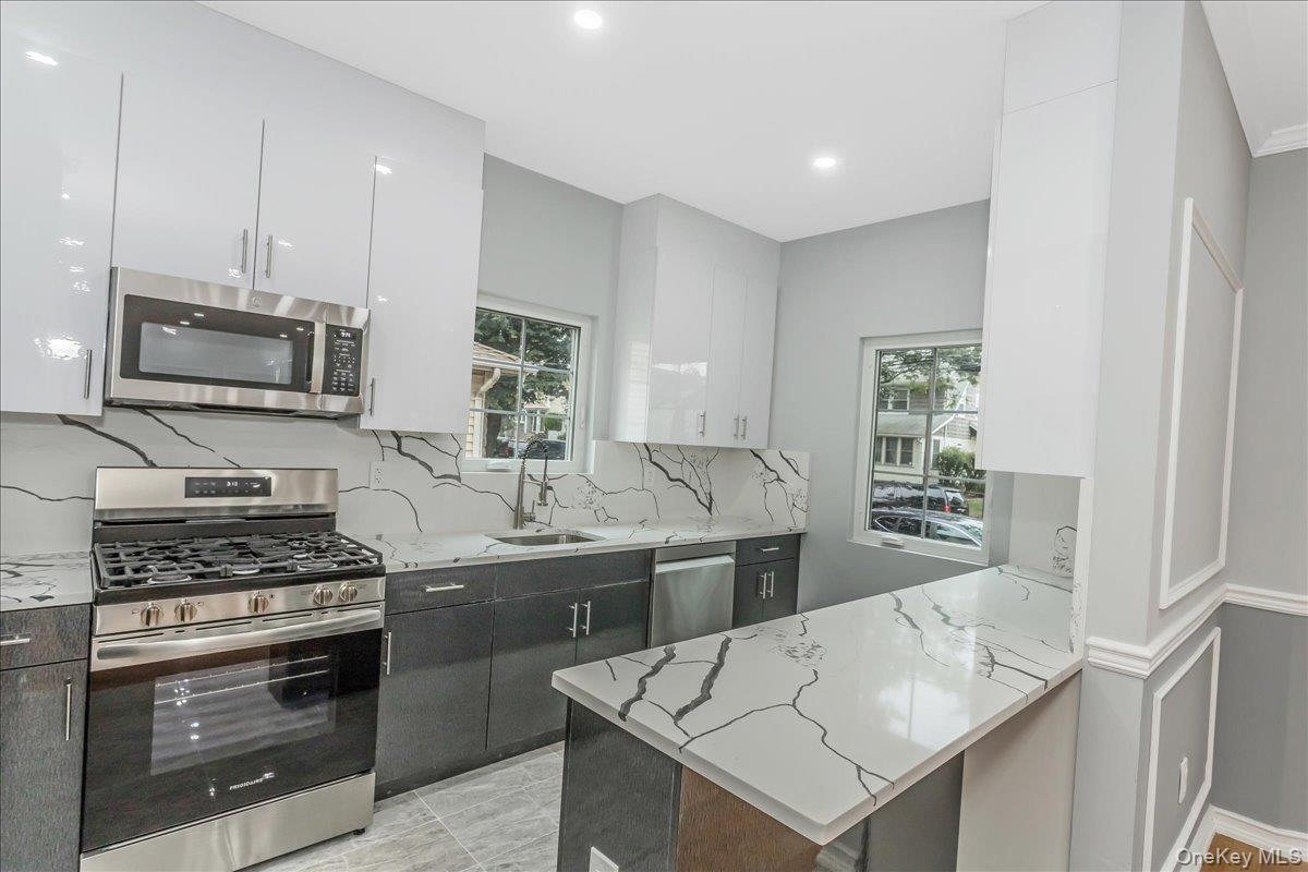 243-36 Caney Road Queens, NY 11422 - Photo 6 of 30 a kitchen with stainless steel appliances kitchen island a stove sink and microwave