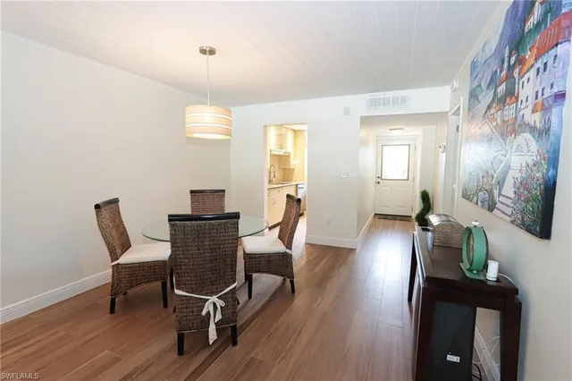 a dining room with wooden floor a chandelier a wooden table and chairs