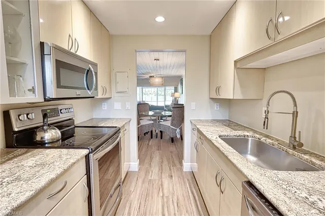 a kitchen with granite countertop stainless steel appliances sink stove microwave and cabinets