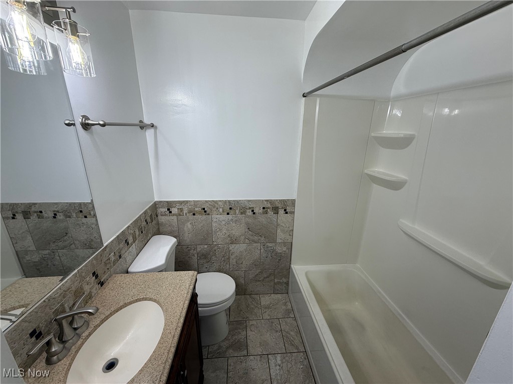6475 Broadview Road Independence, OH 44131 - Photo 19 of 29 Full bath with bathing tub / shower combination, vanity, tile walls, and a wainscoted wall
