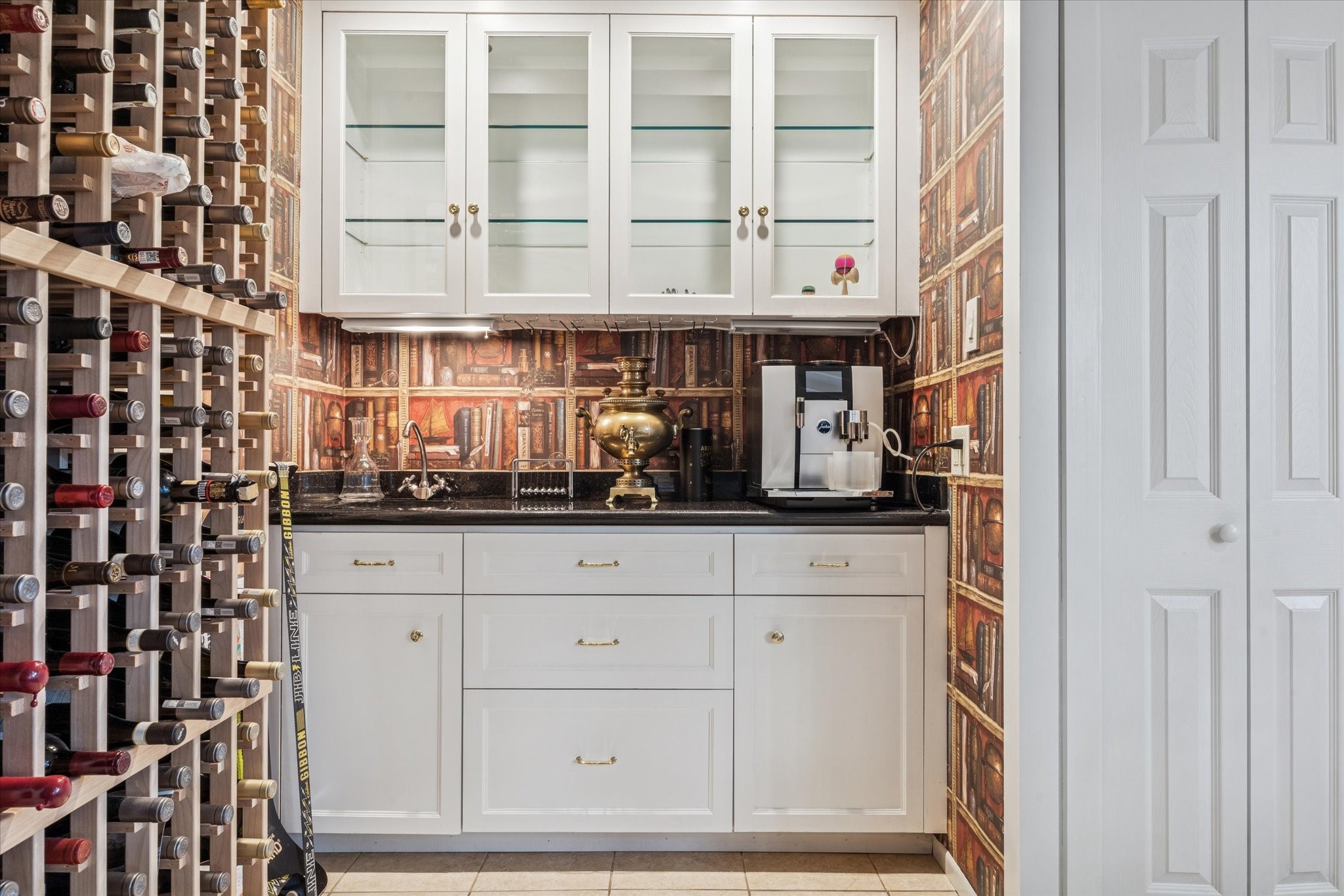 2401 Maconda Lane Houston, TX 77027 - Photo 9 of 20 Closer view of the WET BAR with built-in bottle storage, painted cabinets/drawers, stone counter/backsplash, built in glass front cabinets with glass shelving and under cabinet lighting, papered walls.