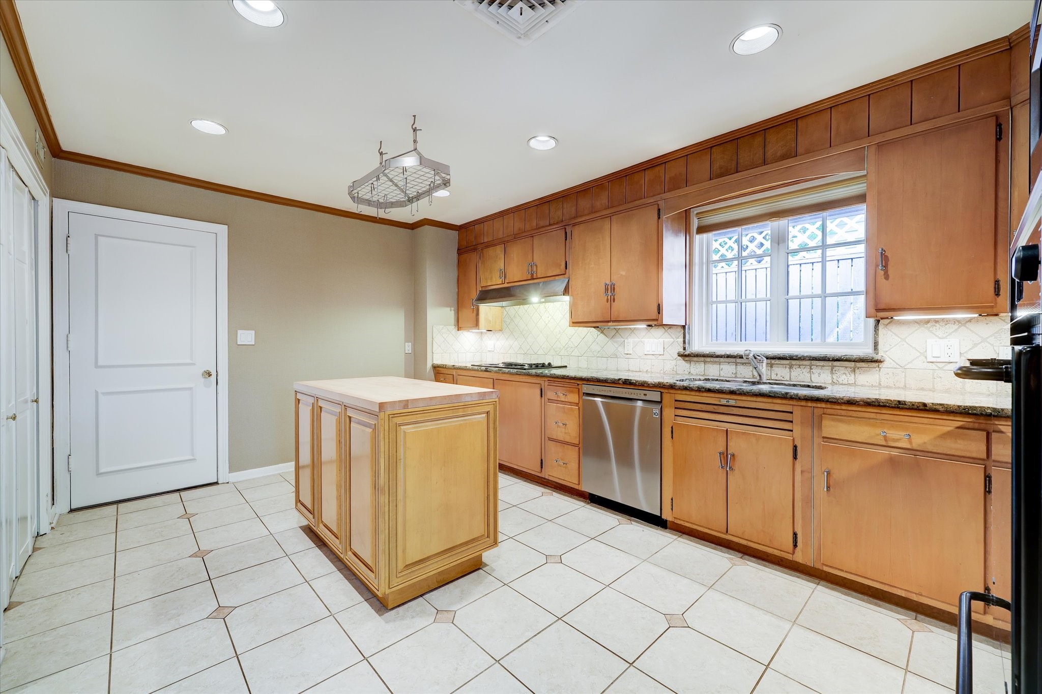2401 Maconda Lane Houston, TX 77027 - Photo 5 of 20 The spacious KITCHEN (16 X 13) includes a center island, (pot hanging rack above), dual ovens, granite counters/stone backsplash, recessed lighting, stone flooring with decorative accents.