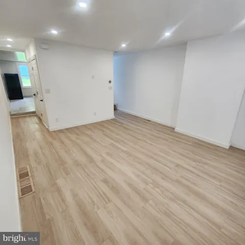 an empty room with wooden floor and a bathroom