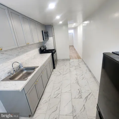 a kitchen with granite countertop a sink a stove and refrigerator