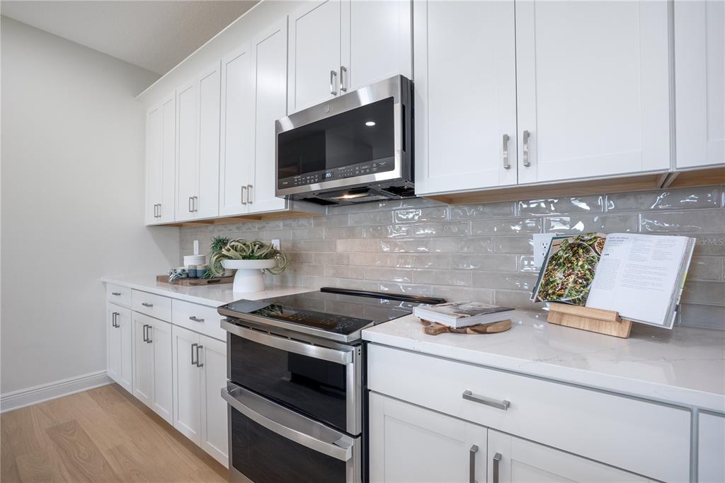 17966 Broadleaf Loop Venice, FL 34293 - Photo 7 of 19 a kitchen with stainless steel appliances granite countertop a sink a stove and microwave with wooden floor