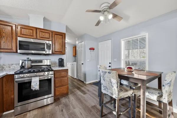 a kitchen with stainless steel appliances a stove a microwave oven a sink dishwasher and a dining table with wooden floor