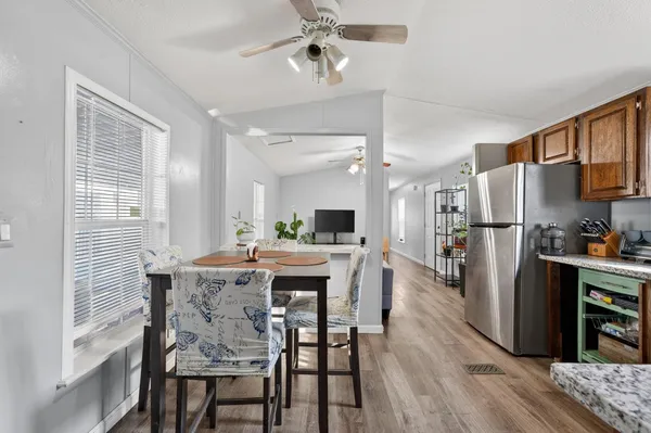 a kitchen with stainless steel appliances granite countertop a dining table chairs refrigerator and cabinets