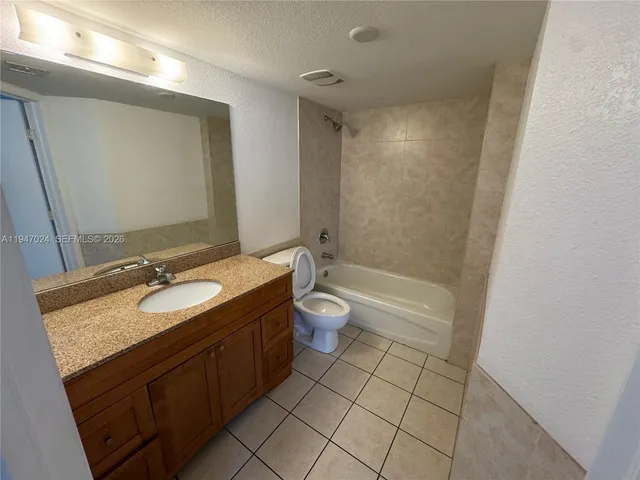 a bathroom with a granite countertop sink toilet a large mirror a shower and a bathtub