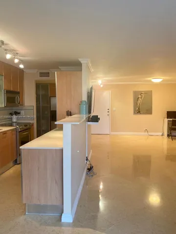 a view of a kitchen with kitchen island a sink a counter top space and stainless steel appliances