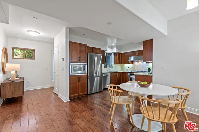 a kitchen with stainless steel appliances a dining table chairs and wooden floor