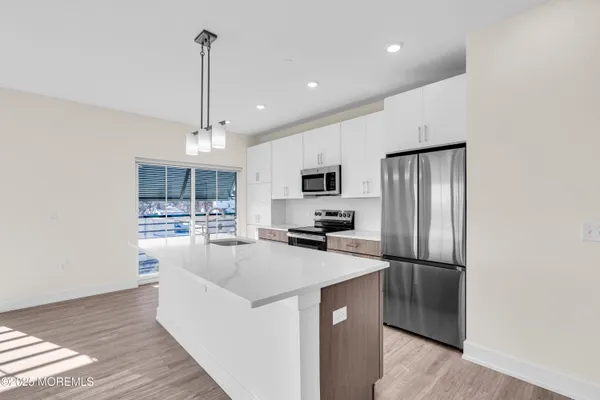 a living room with couches chandelier and a dining table with wooden floor
