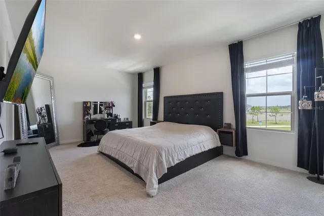 a bedroom with a large bed and a flat tv screen on dresser