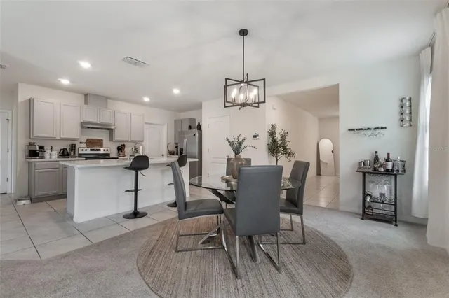 a view of a dining room and livingroom with furniture wooden floor a chandelier