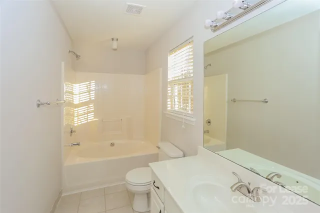 a bathroom with a bathtub toilet sink vanity and windows