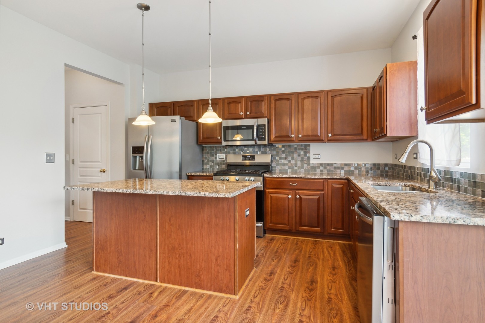 11751 Glenn Circle Plainfield, IL 60585 - Photo 4 of 19 a kitchen with stainless steel appliances granite countertop a sink a stove and a wooden floors