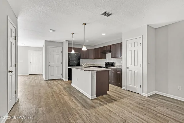 a view of kitchen with stainless steel appliances wooden floor and cabinets