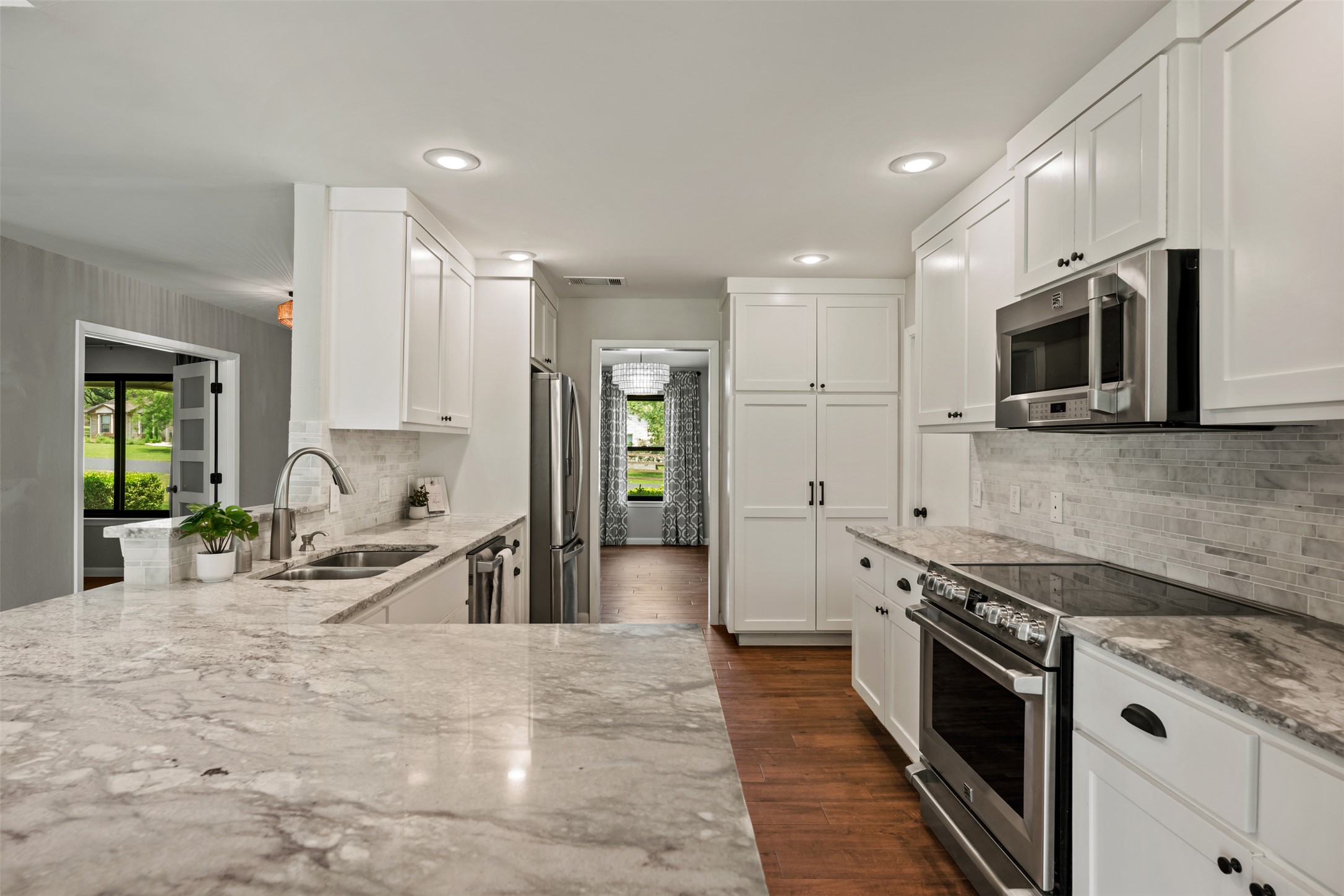 1600 Pin Oak Lane Round Rock, TX 78681 - Photo 17 of 40 Bright kitchen featuring white shaker cabinetry, patterned stone countertops, stainless steel appliances, a mosaic tile backsplash, and recessed lighting