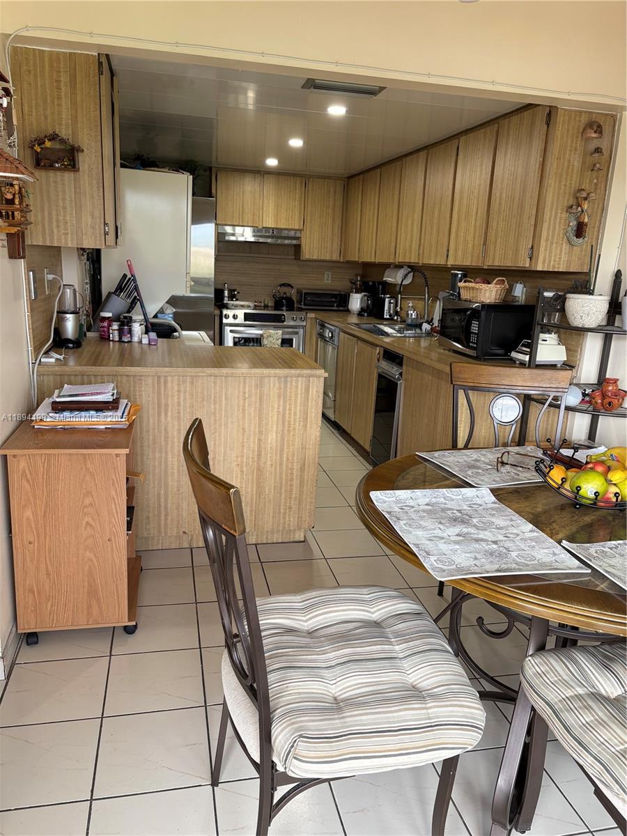 1350 Southwest 122nd Avenue, Unit 423 Miami, FL 33184 - Photo 3 of 8 a kitchen with a table chairs sink and cabinets
