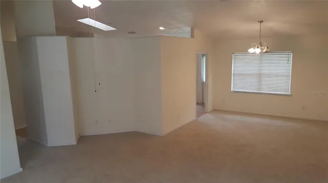 an empty room with chandelier fan and windows