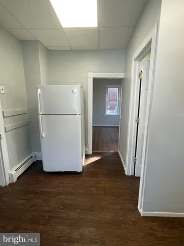 a view of a refrigerator in kitchen and an empty room