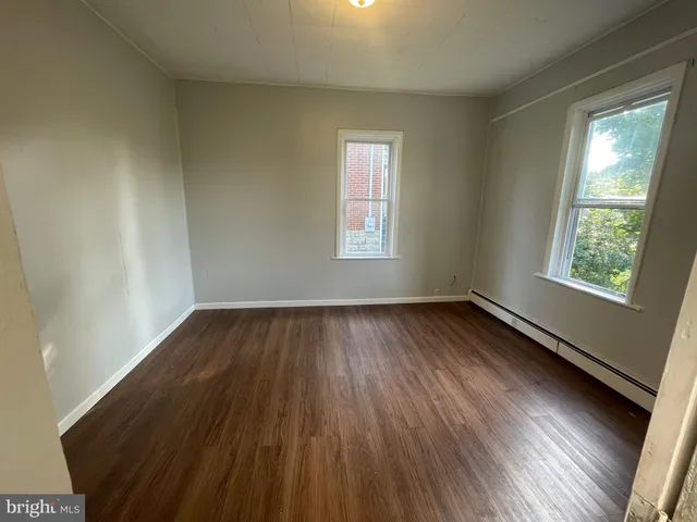 a view of an empty room and wooden floor and window
