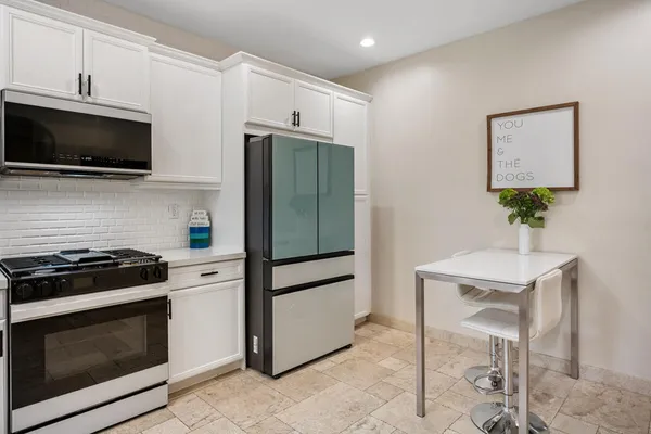 a kitchen with stainless steel appliances white cabinets and stove top oven