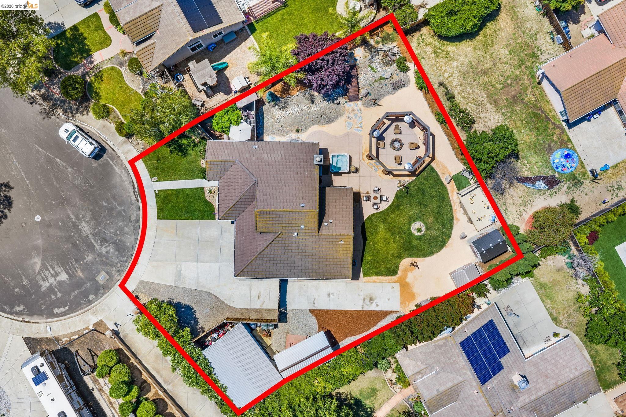 1186 El Rio Court Livermore, CA 94551 - Photo 25 of 60 Expansive property featuring a paved driveway, a large octagonal patio with built-in seating, a circular fire pit, a hot tub, and multiple landscaped lawn areas