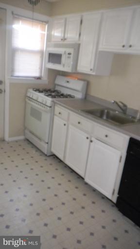 419 Oakwood Road Baltimore, MD 21222 - Photo 10 of 16 a kitchen with a sink a stove cabinets and a window
